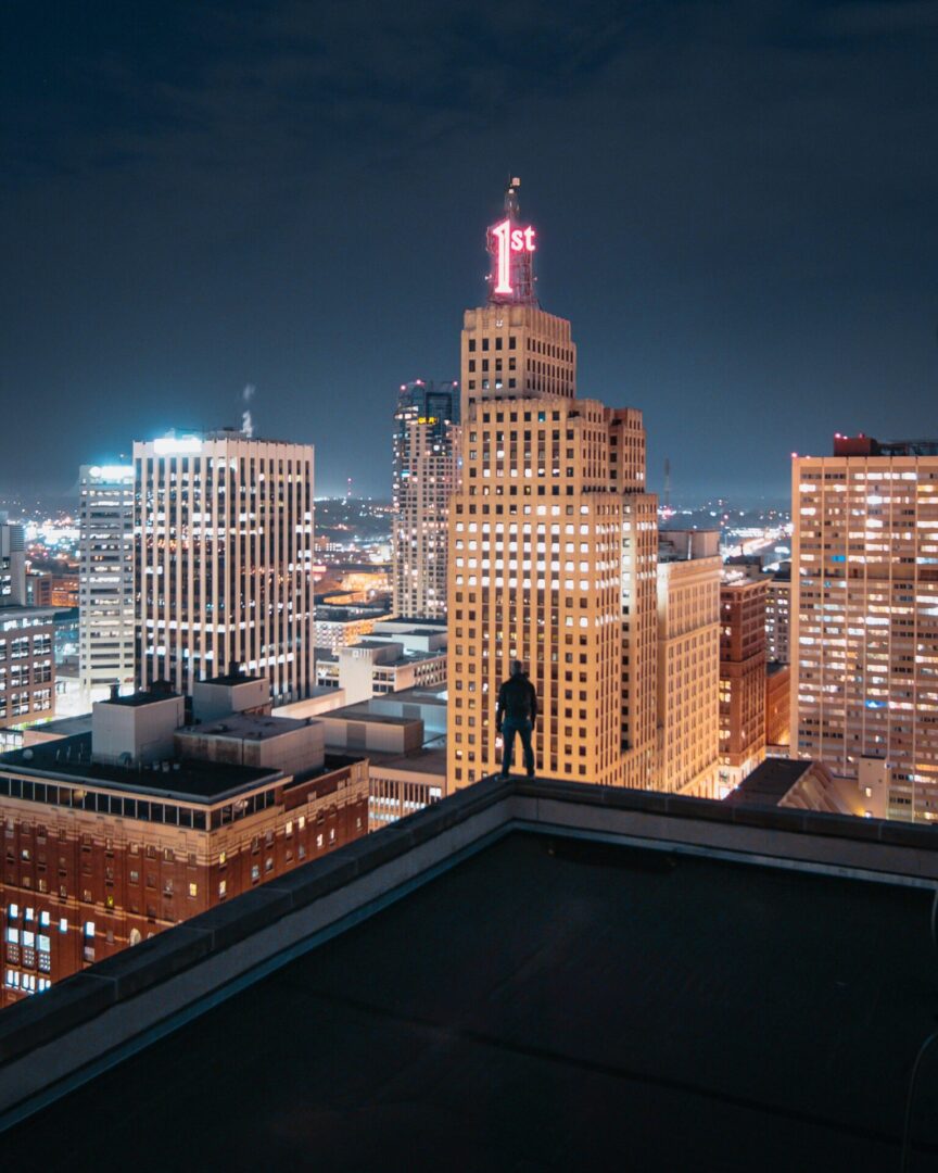 pexels-josh-hild-1270765-3216084 (1) A person standing on top of a building at night.